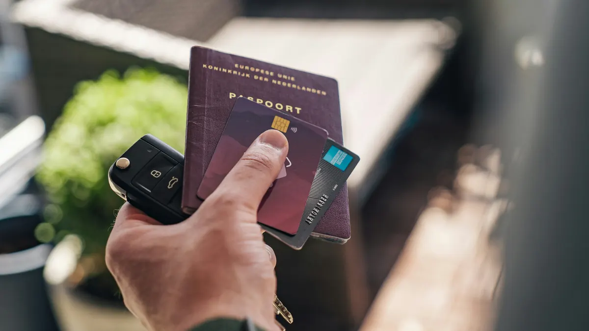 Mano sosteniendo pasaportes, tarjetas y una llave de coche, documentación necesaria para conducir legalmente