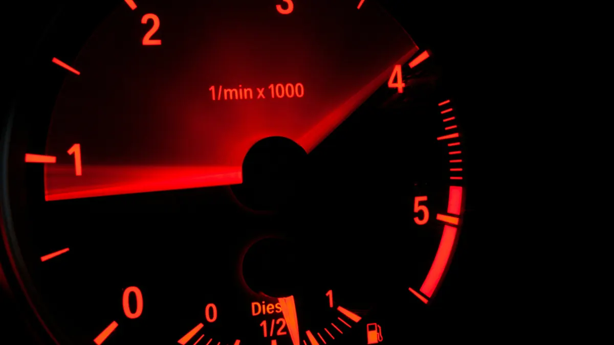 Cuentarrevoluciones iluminado en rojo en el salpicadero de un coche a alta velocidad